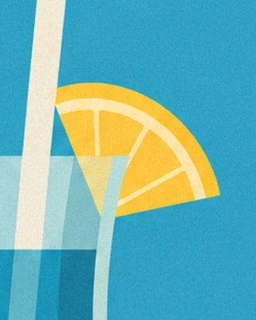Une tranche de citron jaune au bord du verre bleu, près d’une paille claire